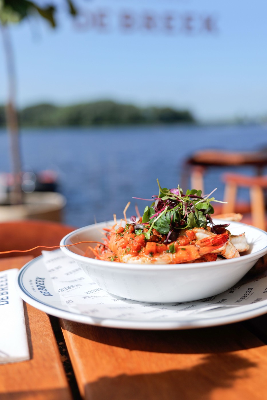 Gegrilde gamba's op tafel bij Paviljoen De Breek, met uitzicht over het water